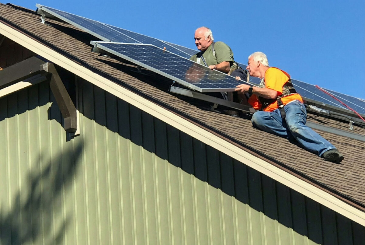 Two men on a rooftop installing solar panels from an Unbound Solar kit