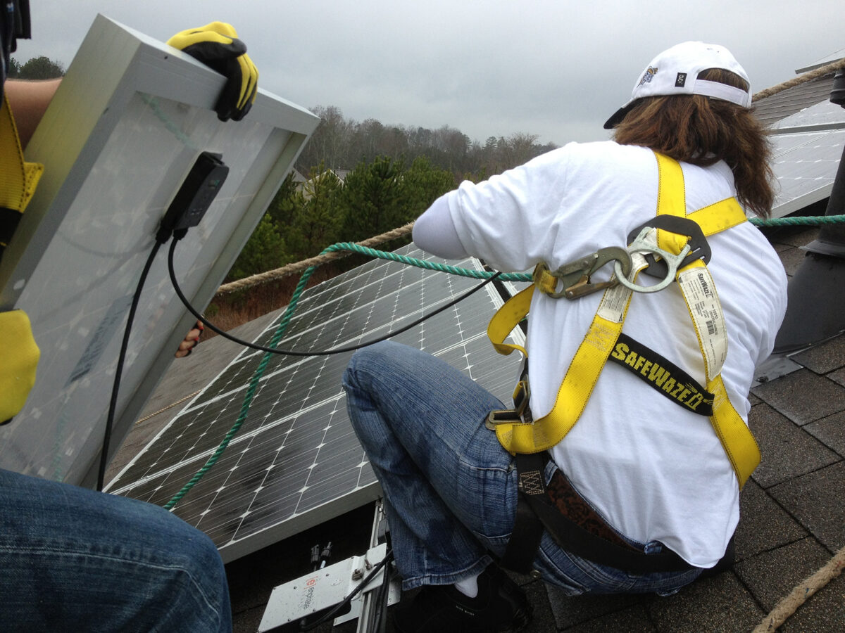 Solar installers laying panels down onto racks on a rooftop