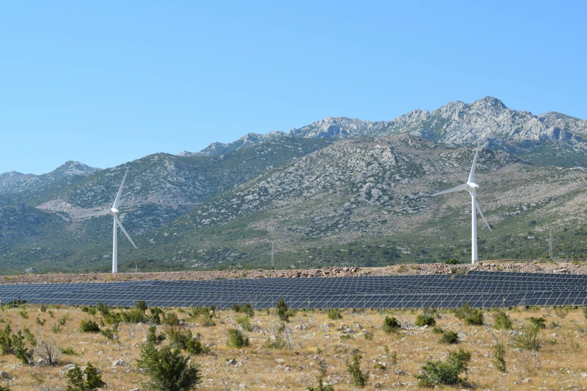 wind turbines and a large solar array in a dry, mountainous landscape